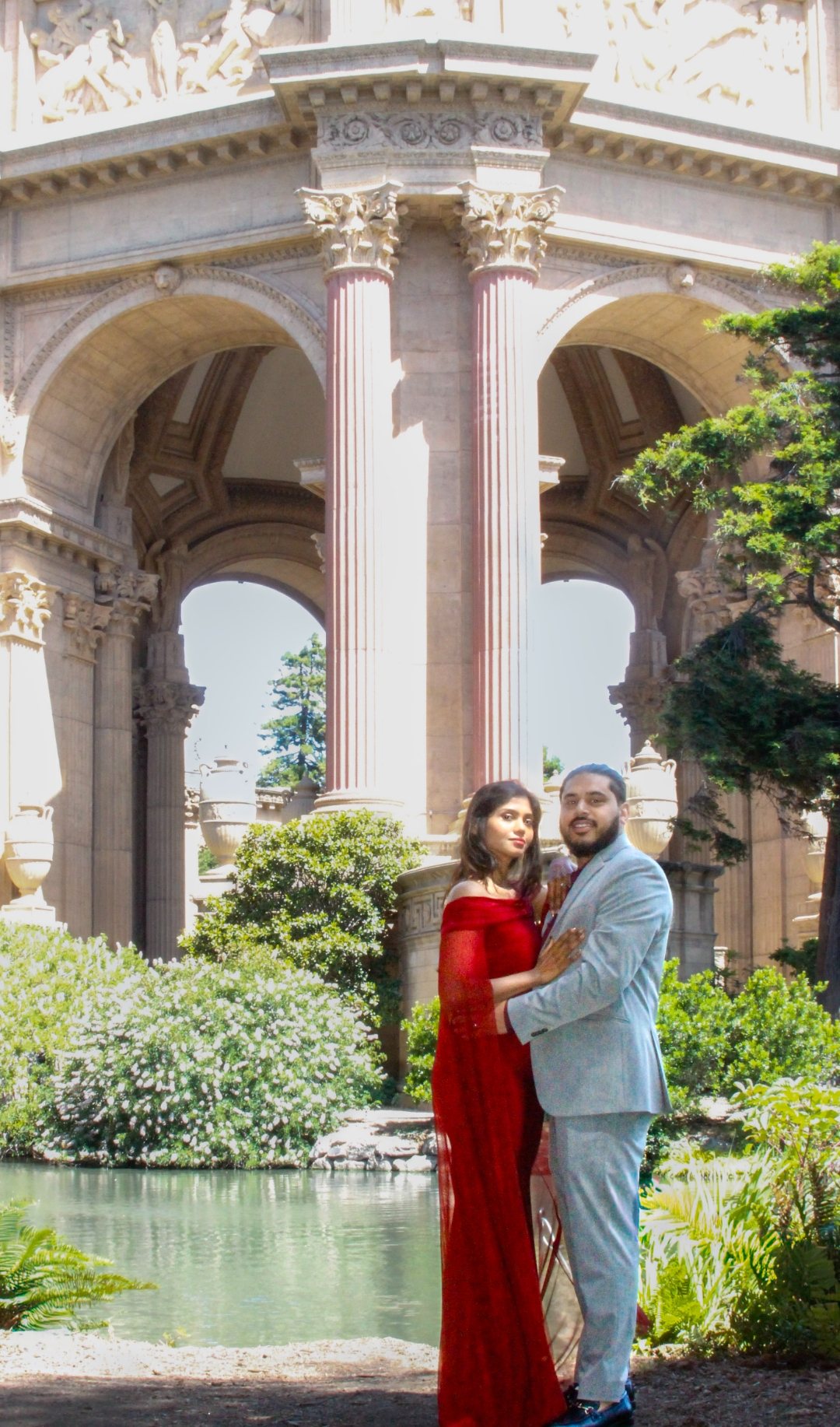 Prunella and Johnetan laughing together beneath rose-colored columns