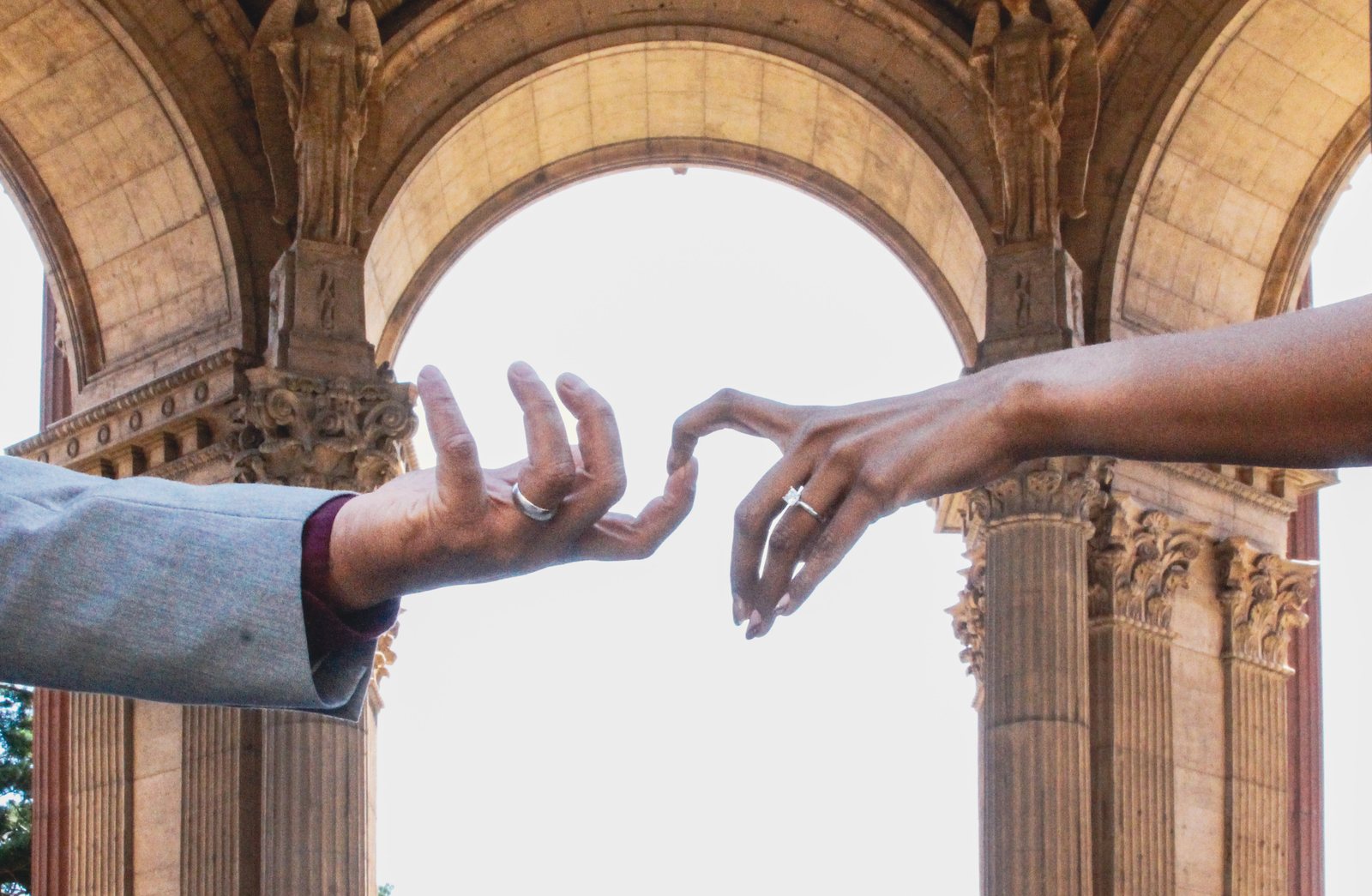 Prunella and Johnetan reaching for each other's hands beneath a stone archway